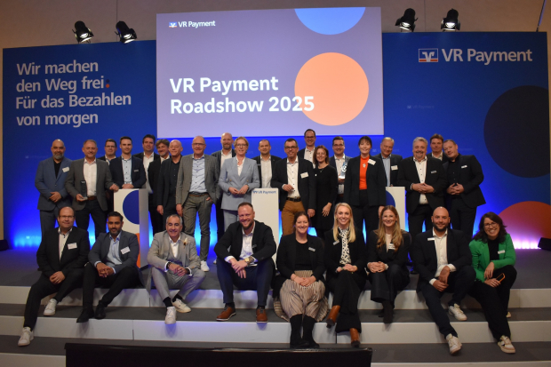 Gruppenfoto auf einer Bühne vor einer Leinwand mit der Aufschrift ‚VR Payment Roadshow 2025‘ und VR-Payment-Branding; die Teilnehmenden stehen und sitzen in Reihen für ein gemeinsames Foto.